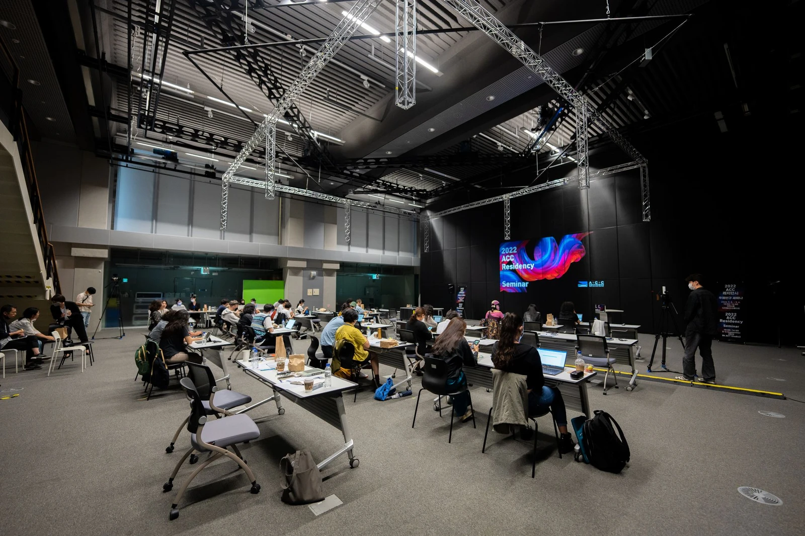 Illustrative photograph of a large seminar audience learning with laptops and presentation screens